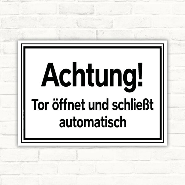 Warnschild mit Text „Achtung! Tor öffnet und schließt automatisch“ in Schwarz-Weiß für automatische Toranlagen.