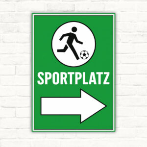 Sportplatz Wegweiser rechts Schild mit Fußballspieler, SPORTPLATZ-Schrift und großem Pfeil nach rechts auf grünem Hintergrund.