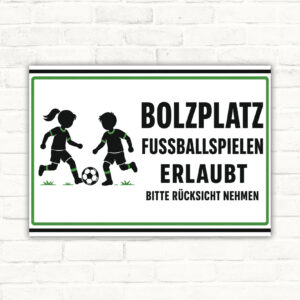 Bolzplatz-Schild mit Fußballkindern und Text „Fussballspielen erlaubt – bitte Rücksicht nehmen“ als Querformat.