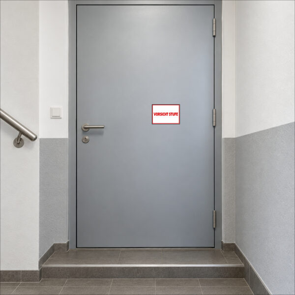 KI-generierte Anwendungsszene: roter Schriftzug VORSICHT STUFE auf weißem Querformat mit rotem Rahmen als Aufkleber auf einer glatten geschlossenen Tür vor dem Treppenabsatz