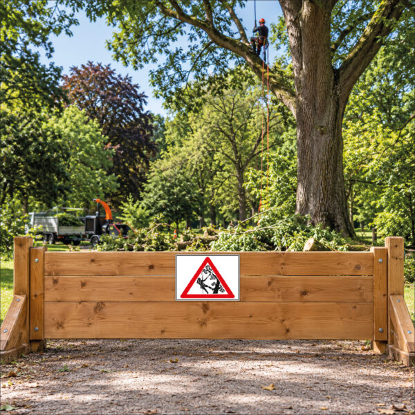 KI-generierte Anwendungsszene: rotes Warndreieck mit einer am Seil arbeitenden Person in einem Baum ohne Text als Schild an einer ebenen Holzabsperrung vor der Baumarbeitsstelle